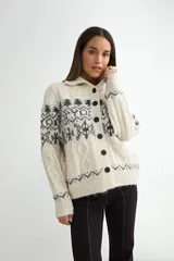 Saco de punto con cuello tipo polo, cierre frontal de botones oscuros y diseño de estampado jacquard en tonos grises y beige. Presenta mangas largas con puños acanalados y textura suave.