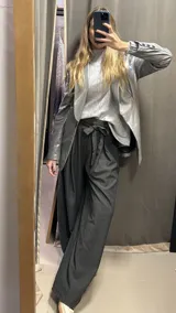 Pantalón negro de corte amplio con pinzas frontales, elástico y lazo en la cintura. Tiene detalles de lurex.