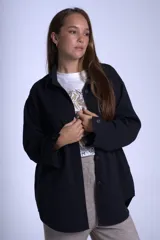 Sobrecamisa color beige confeccionada en gabardina, de corte holgado, con cuello camisero, cierre frontal con botones, dos bolsillos de parche en el pecho y mangas largas con puños abotonados.