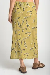 Falda midi color verde oliva con estampado de ramas en negro y blanco. Tiene corte evasé, cintura alta con cordón ajustable y abertura lateral.