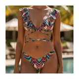 Bikini de dos piezas con estampado geométrico multicolor en tonos turquesa, rojo y naranja. Corpiño triangular con volados en los tirantes y tiras cruzadas para atar en la cintura. Bombacha estilo tanga.