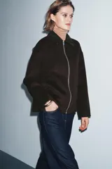Chaqueta de corte recto confeccionada en hilatura con lana, en color marrón oscuro. Presenta cuello clásico en tejido efecto piel de ante, cierre frontal con cremallera metálica y manga larga.