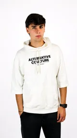 Hoodie de color blanco con mangas tres cuartos, capucha con cordones ajustables y bolsillo frontal tipo canguro. Presenta un estampado gráfico en el pecho con la frase 'Alternative Couture'.