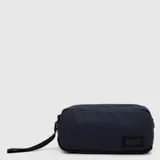 Cartuchera rectangular de diseño minimalista, color azul marino, con cierre principal y correa de mano lateral. Presenta una etiqueta rectangular con el logo de la marca en la parte inferior derecha.