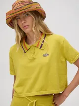 Chomba deportiva tipo crop top de tejido de punto color amarillo verdoso, con cuello camisero a rayas naranjas, rojas y moradas. Presenta un pequeño logo bordado en el pecho.