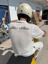 Camisa de waffle color crema con cuello polo, mangas cortas y bordado marrón en la espalda.