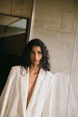 Blazer blanco de lino con cuello solapa, manga larga con hombreras y puños con vuelta estampada. Tiene bolsillos delanteros con solapa y cierre frontal con botón.