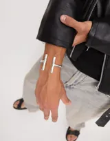 Pulsera rígida de metal plateado marca Uno de 50, con dos barras verticales en los extremos.