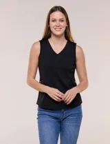 Chaleco blanco sin mangas de estilo smart-casual, con escote en V y costuras verticales de entalle. Cuenta con bolsillos o solapas simuladas a los lados de la cintura decorados con un botón metálico dorado y un largo a la cadera.