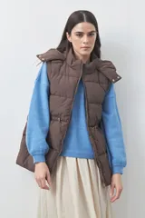 Chaleco puffer negro con diseño acolchado, capucha desmontable y cierre frontal. Cuenta con cordones ajustables en la cintura y bolsillos laterales.