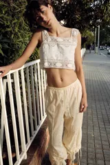 Top crop de algodón con escote cuadrado y tirantes anchos. Presenta bordados florales, aplicaciones de encaje y cierre frontal con botones y lazadas.
