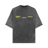 Remera de corte oversize con efecto acid wash en color gris oscuro. Presenta estampado gráfico en color amarillo en el frente con el logo de la marca y detalles de texto.