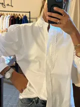 Camisa blanca de algodón con cuello mao, mangas largas abullonadas y detalle de encaje vertical en el frente.