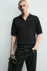 Polo de punto color negro con textura irregular, cuello solapa con abertura frontal, manga corta y acabados en rib, de corte relaxed fit.