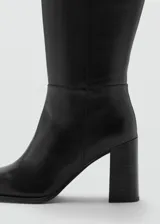 Bota de caña alta confeccionada en piel bovina, con diseño de punta fina y tacón bloque.