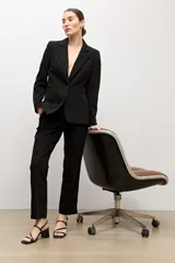 Blazer negro de corte clásico con solapas de muesca, cierre de un botón frontal y bolsillos de ojal con solapa.