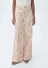 Pantalón jeans de corte wide leg y tiro alto, confeccionado en algodón con estampado floral en tonos suaves. Presenta diseño de cinco bolsillos, cierre frontal con cremallera y botón, y trabillas en la cintura.