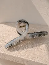 Pinza de pelo con diseño geométrico abierto, en tono gris marmolado.