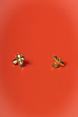 Aros tipo stud con diseño de flor de cuatro pétalos en acabado dorado brillante.