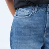 Jean de corte regular y cintura alta, confeccionado en denim azul con lavado stonewash. Presenta un diseño de pierna recta con un dobladillo ancho en la parte inferior.