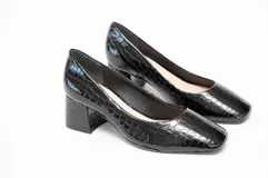 Zapato de salón con tacón cuadrado y grueso, confeccionado en cuero con acabado grabado efecto cocodrilo. Presenta una puntera ligeramente cuadrada y redondeada, ofreciendo un diseño sofisticado y estable.