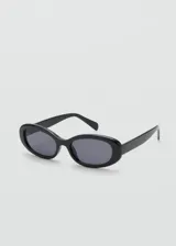 Lentes de sol con armazón de policarbonato negro y diseño de montura ovalada angosta estilo retro.