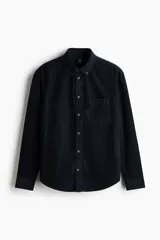 Camisa de pana de algodón suave color negro, con cuello americano, bolsillo superior en el pecho y cierre frontal de botones.