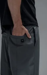 Pantalón de corte oversize color gris carbón, confeccionado en microfibra técnica. Presenta cintura elástica, bolsillos laterales, un bolsillo cargo con cierre de broche y sistema de elásticos con tancas en los tobillos para regular la apertura.