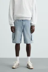 Bermuda de denim de algodón, color celeste lavado, de corte relajado (relaxed fit). Presenta cinco bolsillos, incluyendo bolsillos cargo plastrón con solapa en las perneras.