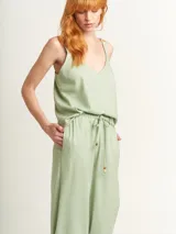 Musculosa verde agua con escote en V, breteles anchos con detalle de argollas de madera y ruedo con flecos.