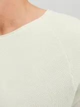 Sweater de punto color crudo, de manga larga y cuello redondo.