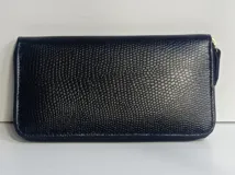 Billetera rectangular de cuero negro con textura granulada y cierre perimetral. Cuenta con múltiples compartimentos internos para tarjetas, documentos y billetes, además de un bolsillo con cierre para monedas y forro interior textil en color rojo.