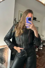Campera corta tipo bomber de cuero negro con costuras desgastadas y puños de punto.
