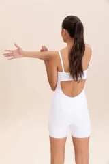 Jumpsuit corto de diseño ajustado con escote cuadrado y breteles finos. Confeccionado en tejido técnico con acabado ligeramente brillante y textura acanalada, ofrece compresión media y alta elasticidad.