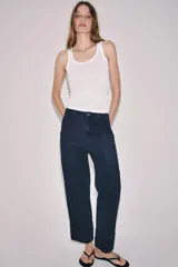 Pantalón worker de tiro medio de Zara Woman Collection, confeccionado en denim azul oscuro con detalles de combinación de tejidos a tono. Presenta cintura con trabillas, bolsillos laterales de plastrón, bajo acabado en vuelta y cierre frontal con cremallera y botón.