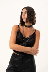 Top de satén negro con escote en V, decorado con detalles de encaje floral en el escote y en el ruedo. Presenta breteles finos ajustables y un corte asimétrico en la parte inferior.