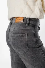 Jean de corte recto y tiro alto, con acabado lavado en tono gris oscuro. Presenta cierre frontal con botón y cremallera, además de bolsillos laterales y traseros.