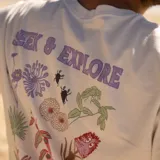 Remera color crema de algodón peinado con cuello redondo y estampado pequeño en el pecho con el logo de la marca Roark y la frase "Seek & Explore".