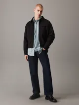 Campera negra de algodón regenerativo con cuello en punta clásico, puños con botones, cierre de cremallera, bolsillos de ojal, bolsillo con cremallera en el pecho, forro completo e insignia con el logo de Calvin Klein en el pecho.