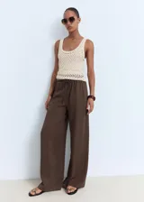 Pantalón wide leg de tiro medio color marrón, confeccionado en lyocell con forro de viscosa. Cuenta con cintura elástica con cordón ajustable y dos bolsillos laterales.