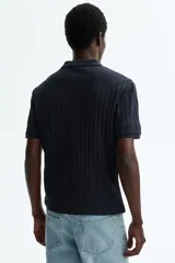 Remera polo de punto texturizado color azul marino, de manga corta, con cuello y cierre frontal parcial de botones, corte slim fit.
