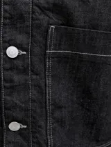 Chaqueta de denim negro con costuras en contraste color blanco, bolsillos frontales con solapa y cierre de botones metálicos.
