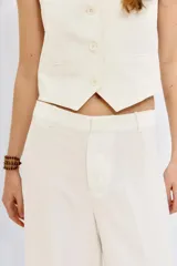 Pantalón de vestir blanco de tiro alto, corte oxford (pierna ancha y recta desde la rodilla) y cierre frontal con botones.