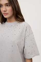 Remera oversize de manga corta y cuello redondo, color gris, con aplicación de strass en degradé en la parte superior.