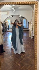 Ruana tejida a mano en lana merino 100%, color verde militar, con diseño de puntos calados y flecos largos en el ruedo.