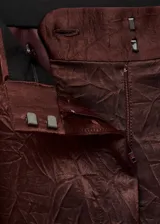 Pantalón de tiro medio en tejido satinado con efecto arrugado y diseño recto. Cuenta con bolsillos laterales, pinzas delanteras y cierre oculto con botón, gancho y cremallera.