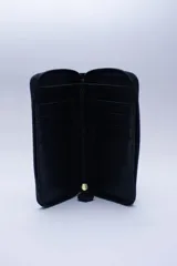 Billetera chica de cuero negro con textura tipo cocodrilo, cierre exterior, bolsillo para monedas con cierre en la parte trasera, múltiples ranuras para tarjetas y billetes, y forro rojo.