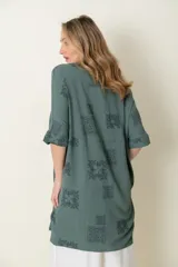 Camisa larga de manga corta, calce holgado, color verde con estampado de motivos en forma de medallones o cuadrados con diseño ornamental.