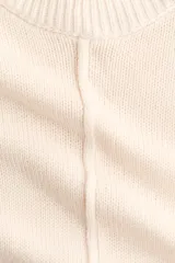 Top de punto color beige, con costura central enlazada al frente, mangas cortas con hombros caídos y ribete acanalado en el cuello, mangas y bajo.