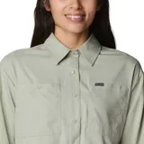 Camisa de manga larga Columbia, color verde claro, con cuello clásico, cierre frontal de botones y dos bolsillos en el pecho. Presenta un diseño técnico con ventilación, ideal para actividades al aire libre.